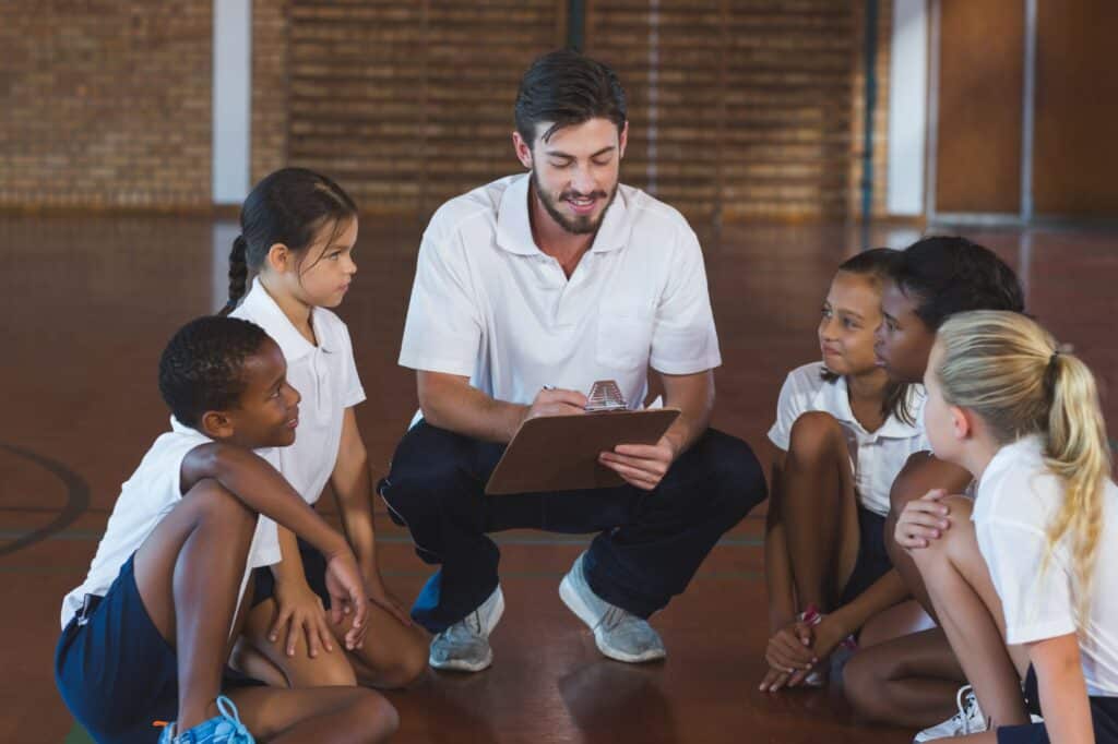 A sports teacher having a discussion with his students