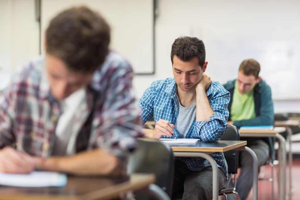 College students writing notes in the classroom in the concept of 'top schools in Uxbridge'.
